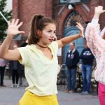 Kaksi tyttöä tanssii Oulun kauppahallin edessä ja taustalla yleisöä katsomassa.