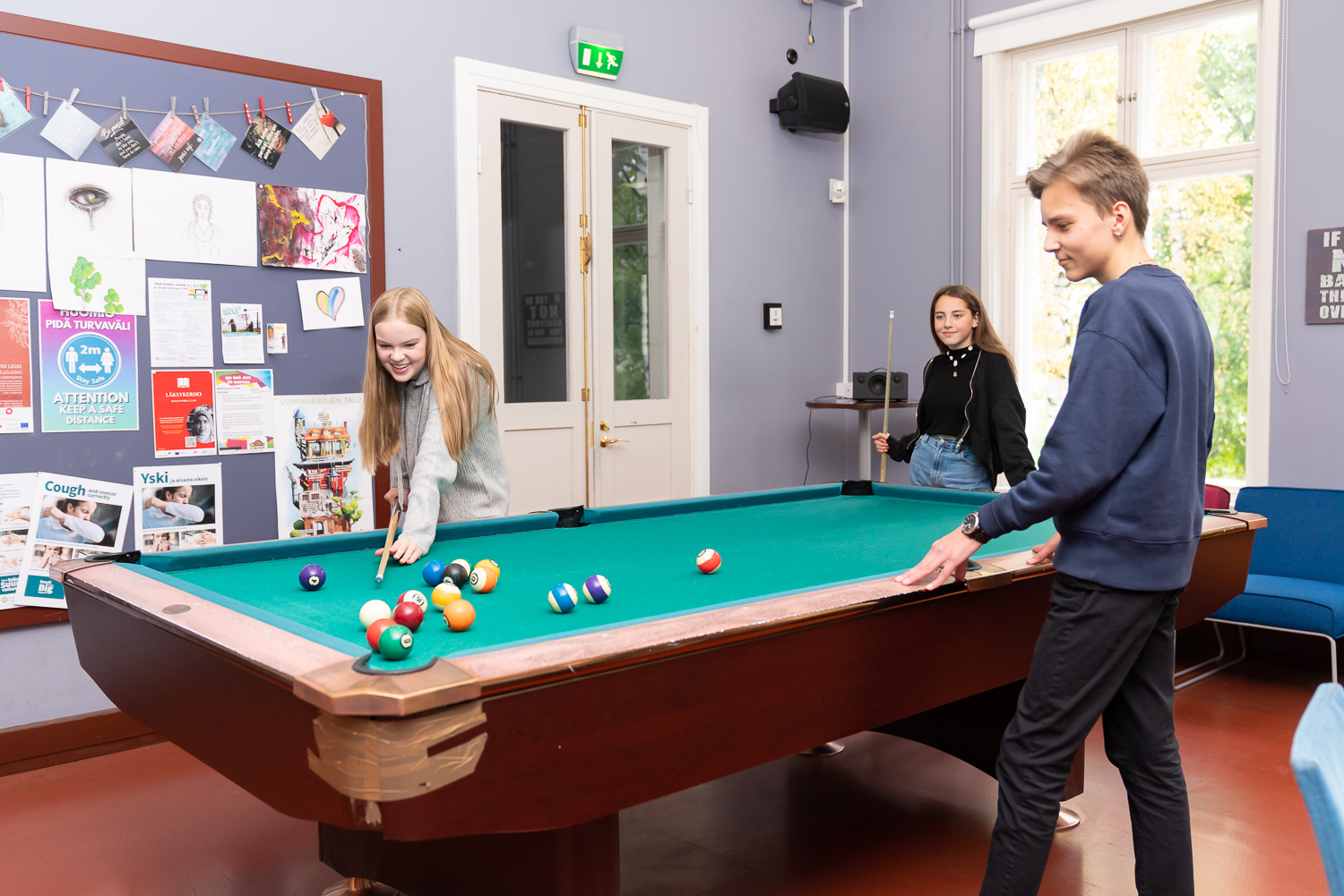 Three young people at the pool table.