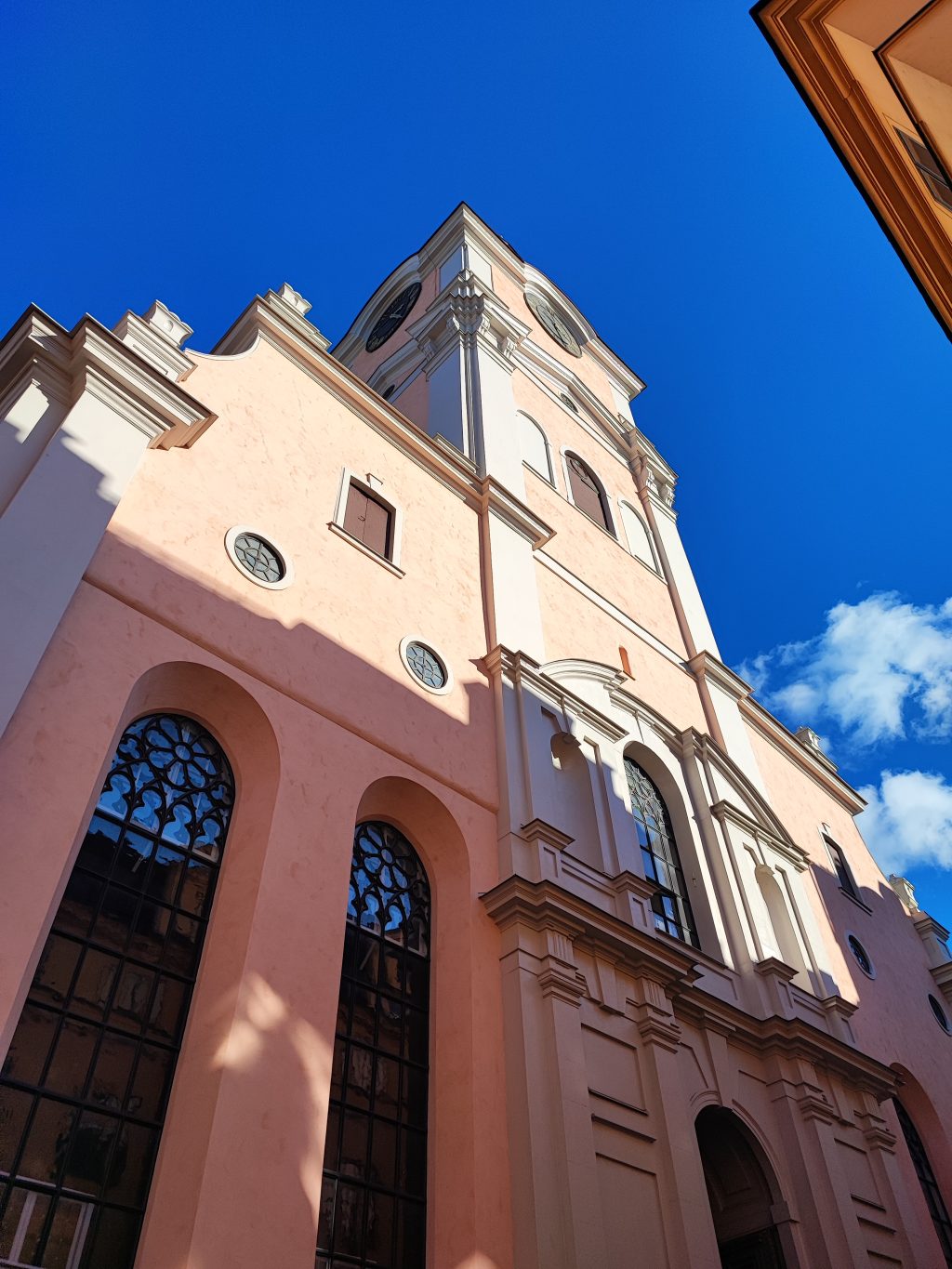 Vaaleanpunavalkoisen historiallisen rakennuksen etuseinä alhaaltapäin kuvattuna.