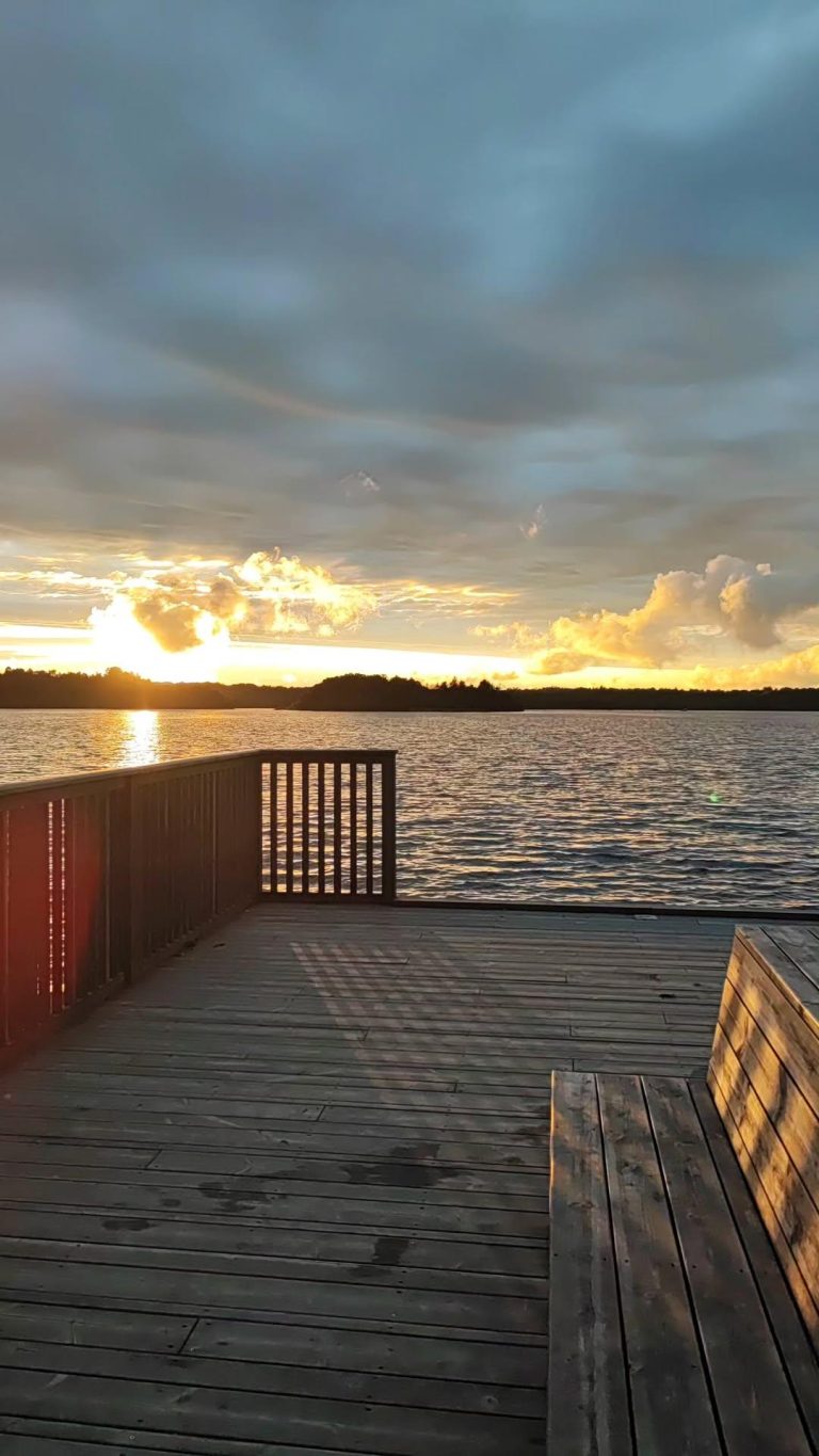 Puinen laituri vesistön rannalla ja taustalla auringonlasku.