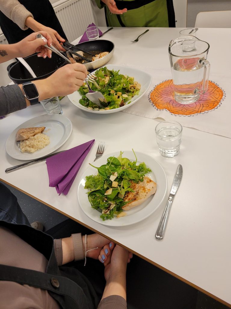 Kokkikerholaisia ruokapöydän ääressä ottamassa salaattia ja kanaa lautasille.