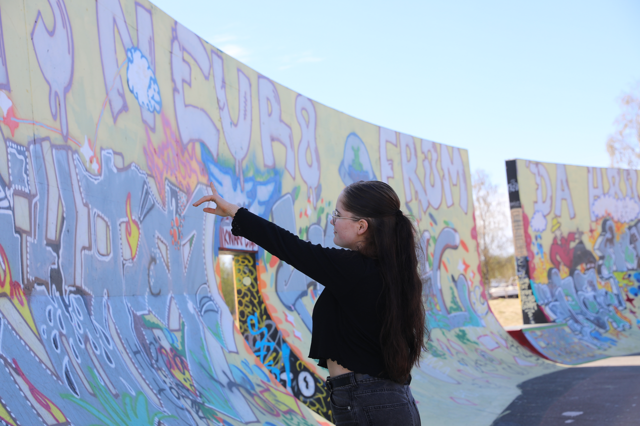 Pitkätukkainen nuori, joka osoittaa sormellaan Hollihaan skeittiparkin graffiteja.