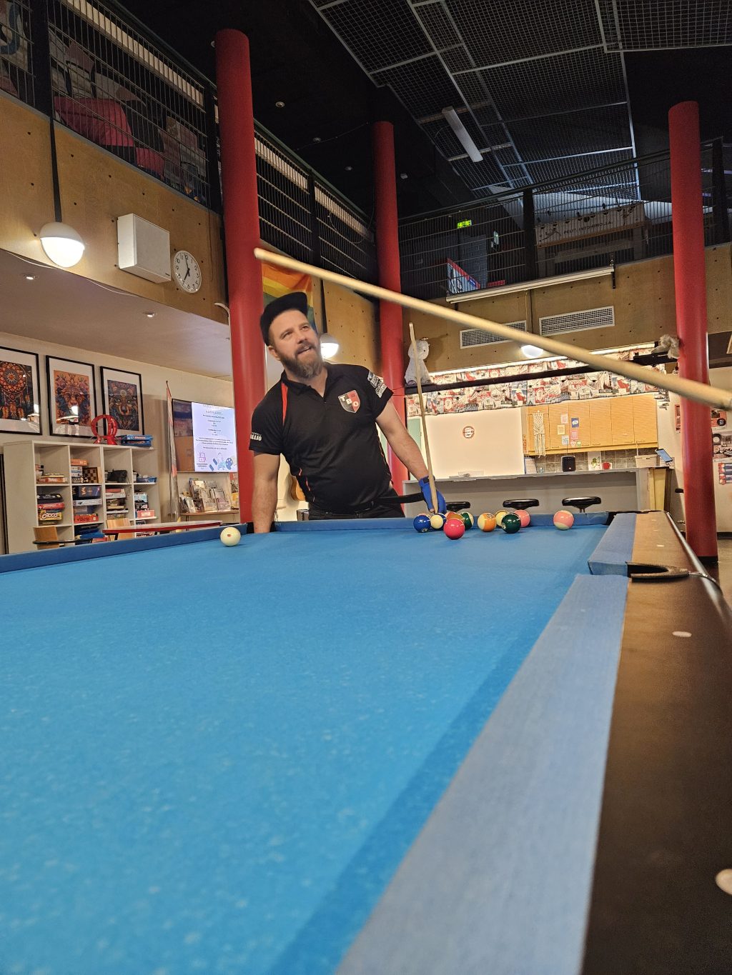 Biljardin ohjaaja seisoo pöydän takana neuvomassa pelaajaa.