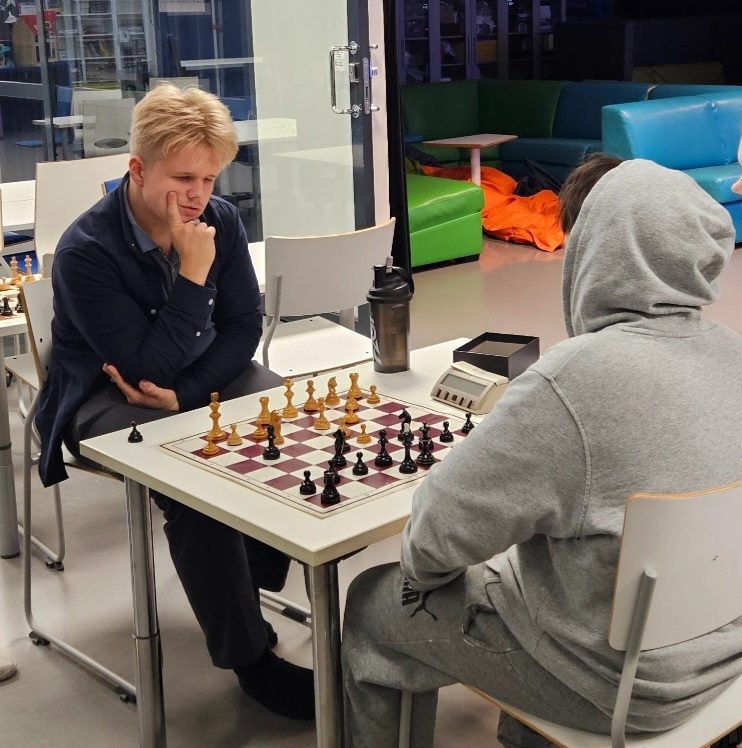 Kaksi nuorta pelaa shakkia vastakkain.