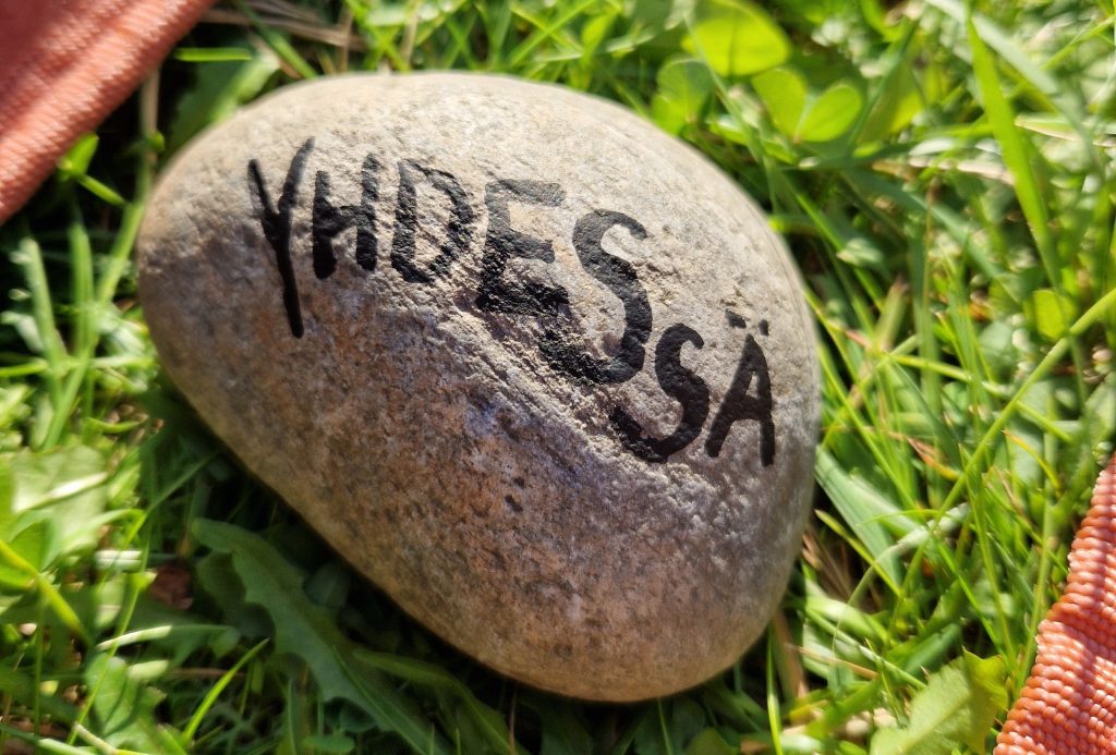 Vihreällä nurmikolla kivi, jossa lukee teksti "yhdessä".