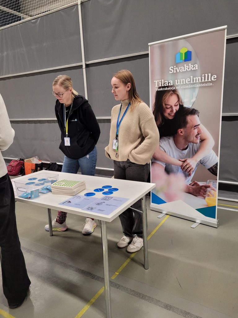 Sivakan esittelypisteellä työntekijät ohjeistavat vedenkulutukseen liittyvää tehtävää.